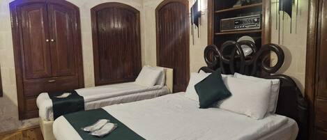A room with two beds, wooden wardrobes, a radio, and a small blue-lit window.
