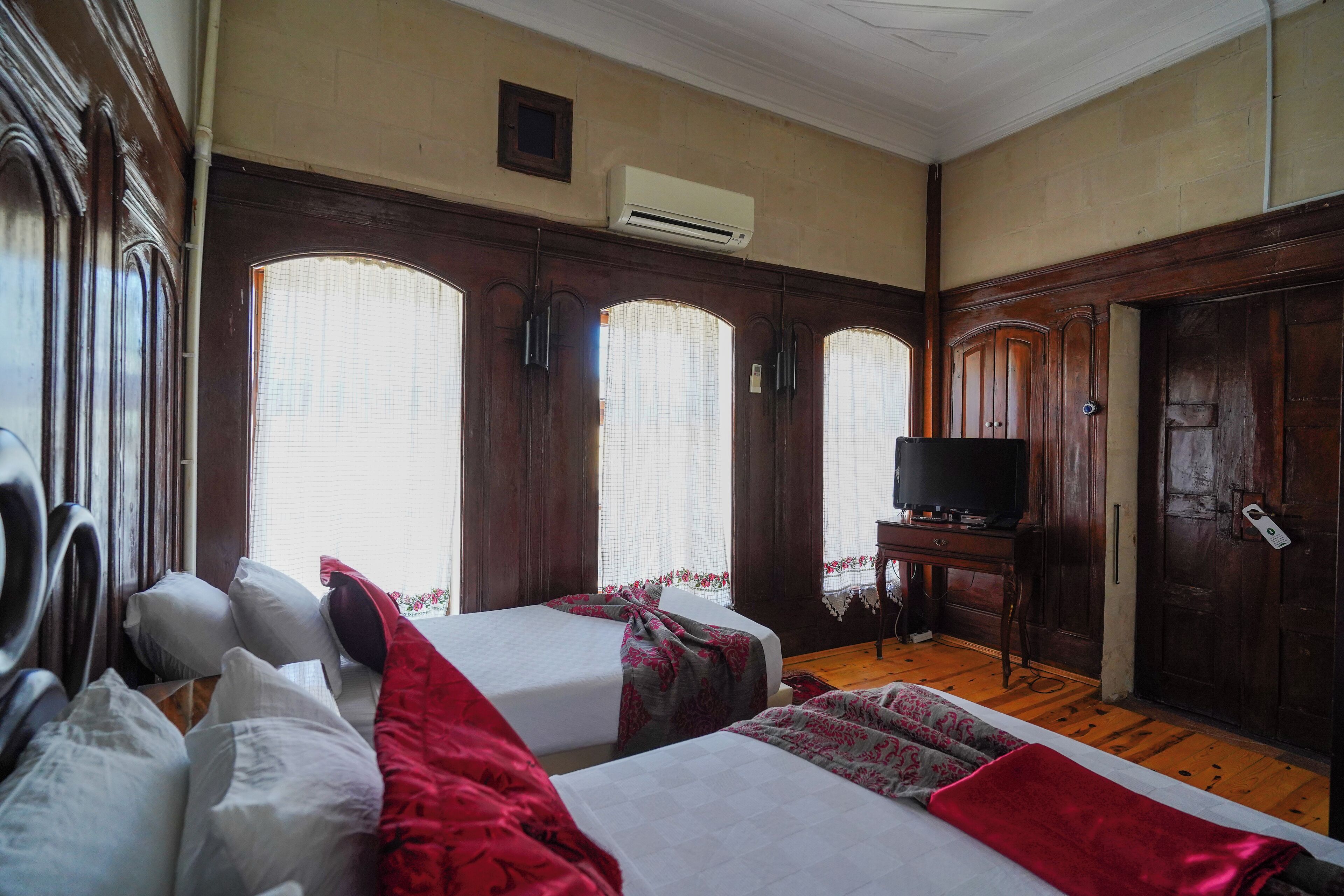 Una habitación de hotel con dos camas, un televisor y un armario de madera.
