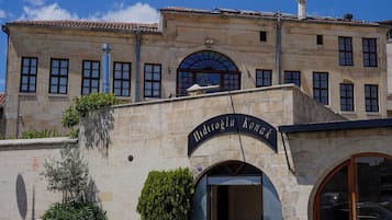 Un edificio con fachada de piedra, un amplio acceso abovedado y un letrero sobre la entrada.
