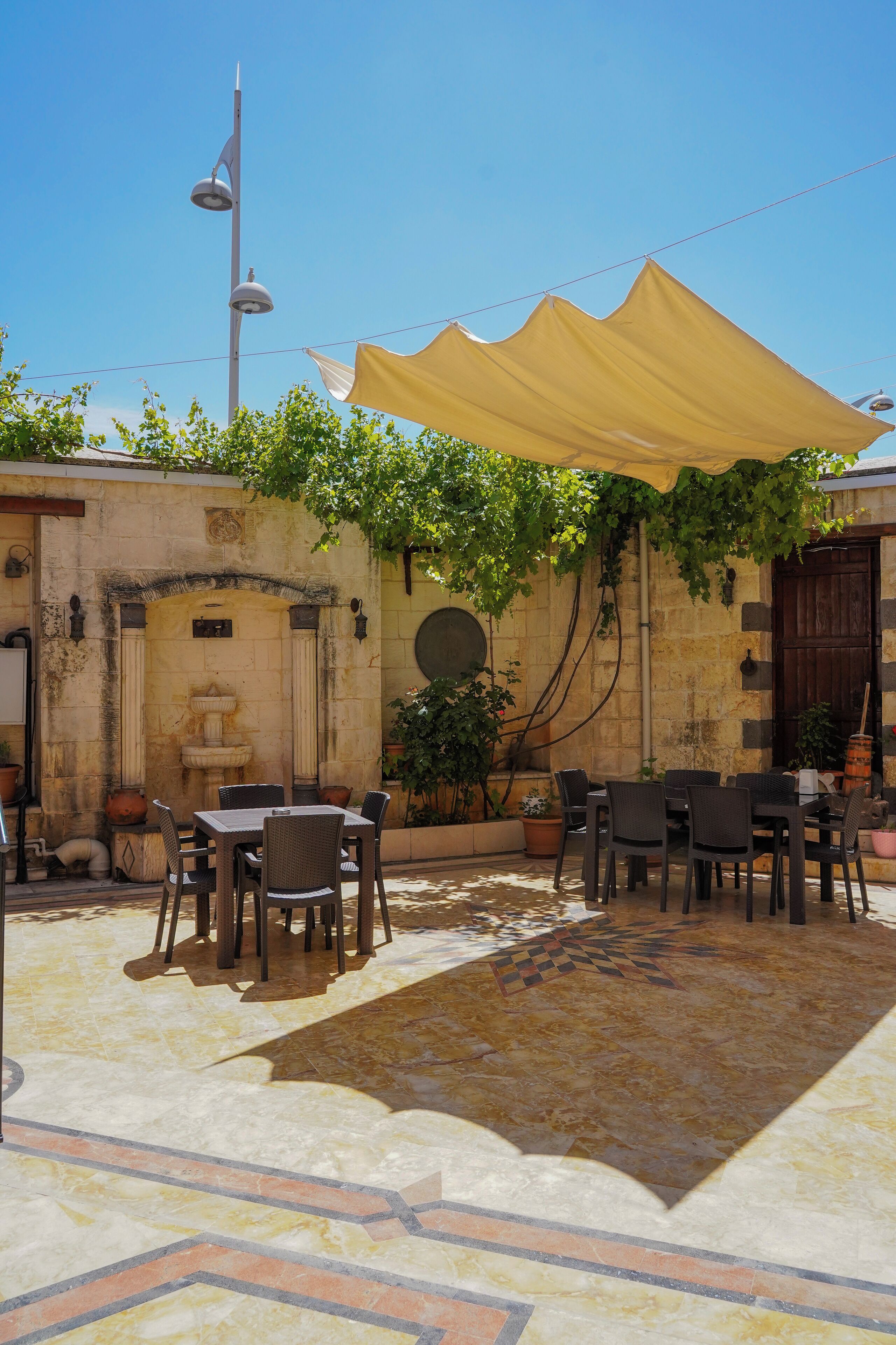 An outdoor patio with stone flooring, tables, chairs, and a yellow canopy.