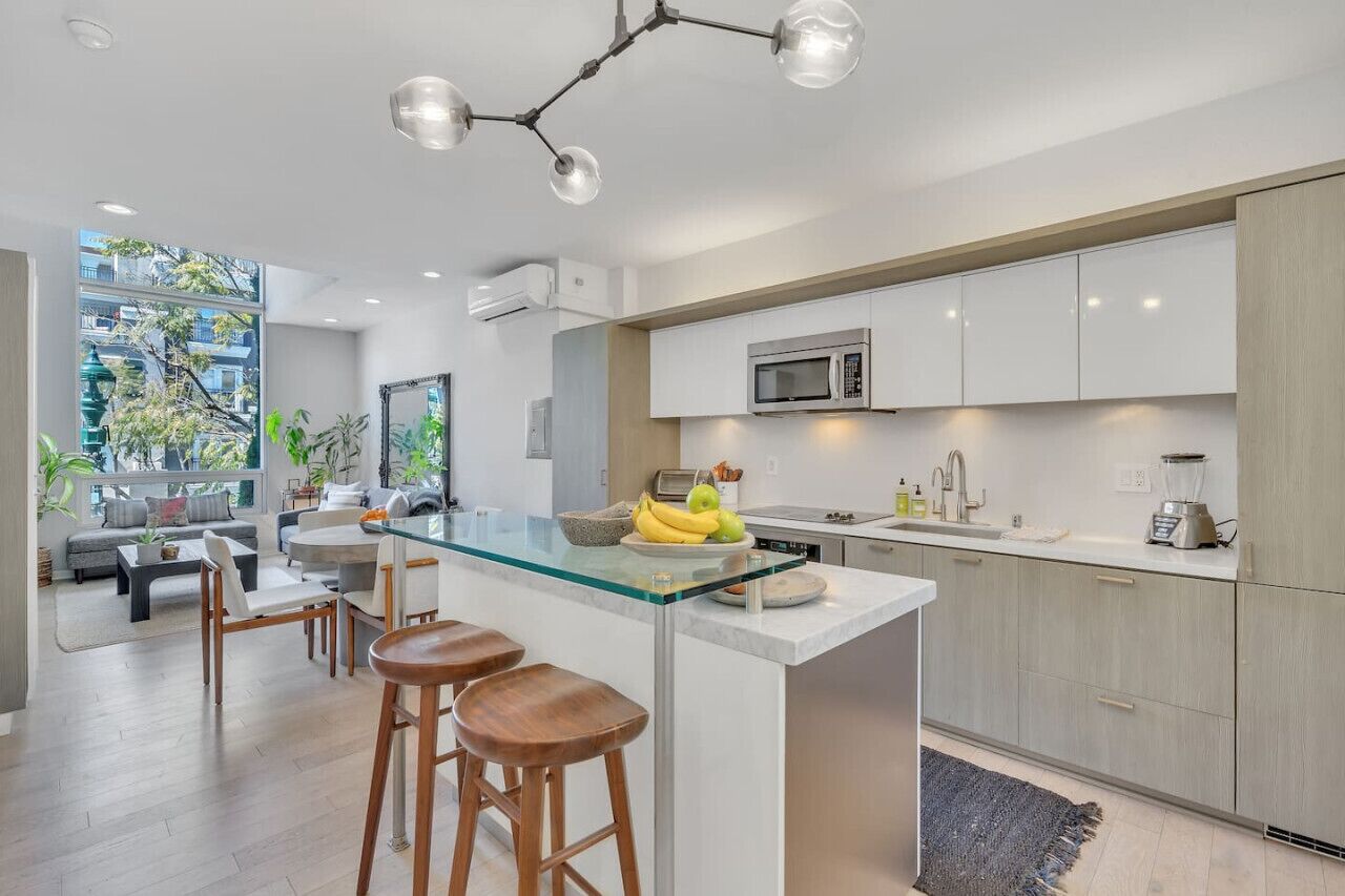 A modern kitchen with a central island, white cabinetry, and a built-in microwave.