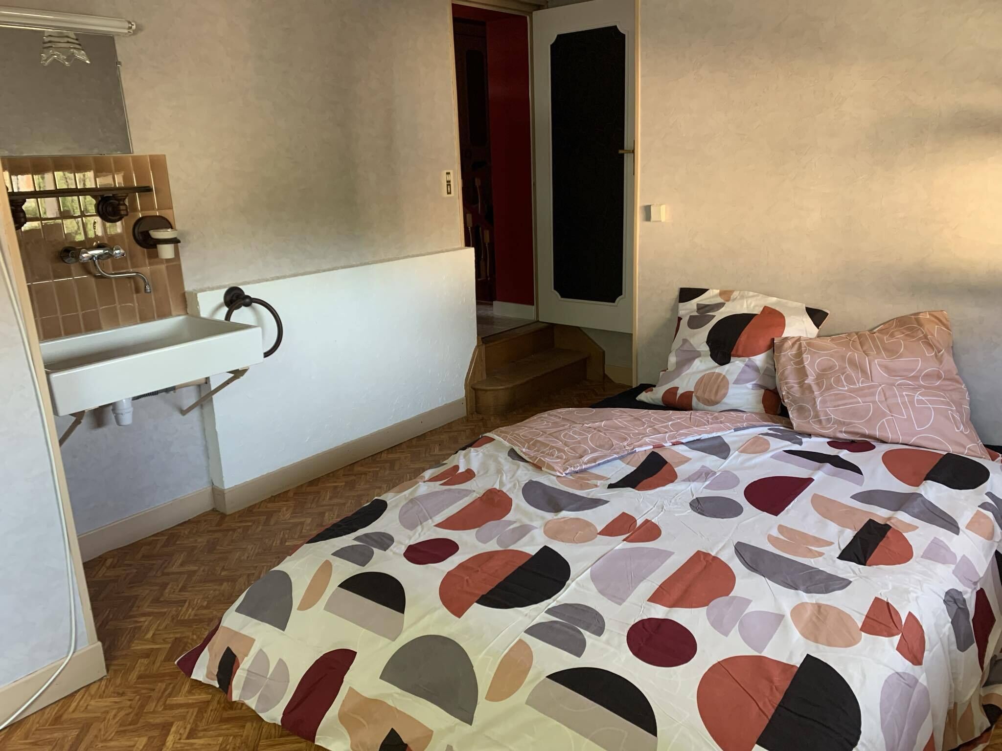 Ein Schlafzimmer mit einem Bett, einem weißen Waschbecken und einem Spiegel.