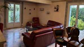 A spacious living room with a red leather sofa, a wooden coffee table, and a chandelier.