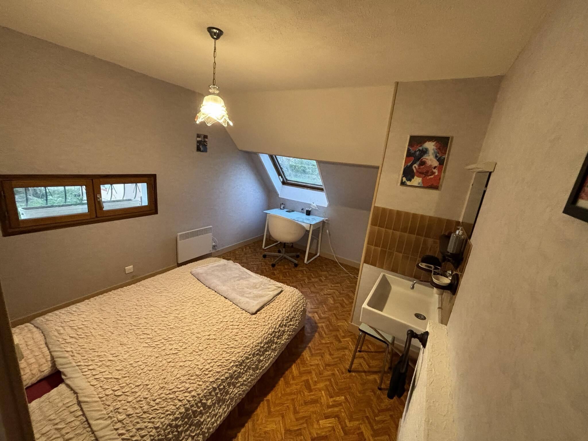 Quarto com cama, escrivaninha, janela e banheiro.