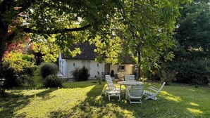 A garden with a white house, a lawn, and outdoor furniture.