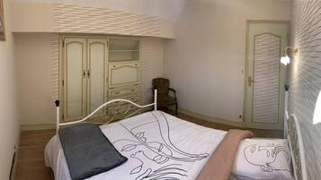 A bedroom with a bed, a chair, a wardrobe, and a door.