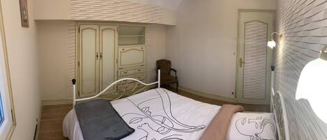 A bedroom with a bed, a chair, a wardrobe, and a door.