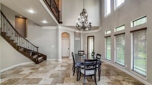 A spacious dining area with a large table and chairs, a chandelier, and a staircase leading to an upper level. - Lakefront with dock, close to April Sound Country Club. BBQ Grill, Laundry (Montgomery)