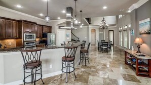 A spacious kitchen with dark wood cabinets, stainless steel appliances, and a central island with bar stools. - Lakefront with dock, close to April Sound Country Club. BBQ Grill, Laundry (Montgomery)