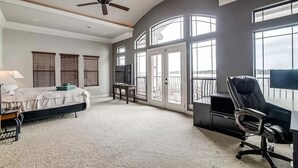 A bedroom with a bed, a desk, a chair, a ceiling fan, and large windows. - Lakefront with dock, close to April Sound Country Club. BBQ Grill, Laundry (Montgomery)