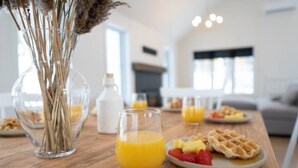 Une table en bois dressée pour le petit-déjeuner, avec des gaufres, des fraises et du jus d’orange.