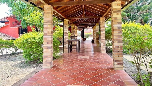 A covered outdoor area with a tiled floor, brick pillars, and a wooden ceiling. - Hotel Cristo Rey Campestre (Los Santos)