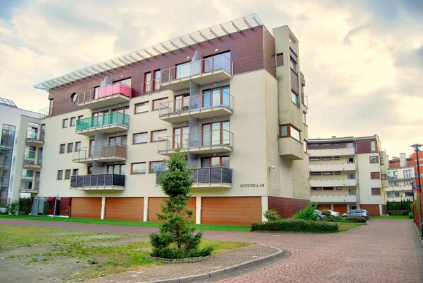 A multi-story residential building with balconies, a small garden, and a paved driveway. - HelApart - Helska Villa (Hel)