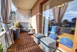 A balcony with wicker furniture, a potted plant, and a view of the street. - HelApart - Helska Villa (Hel)