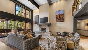 A spacious living area with a fireplace, large windows, and a high ceiling. - Springs #8875 By Summit County Mountain Retreats (Keystone)