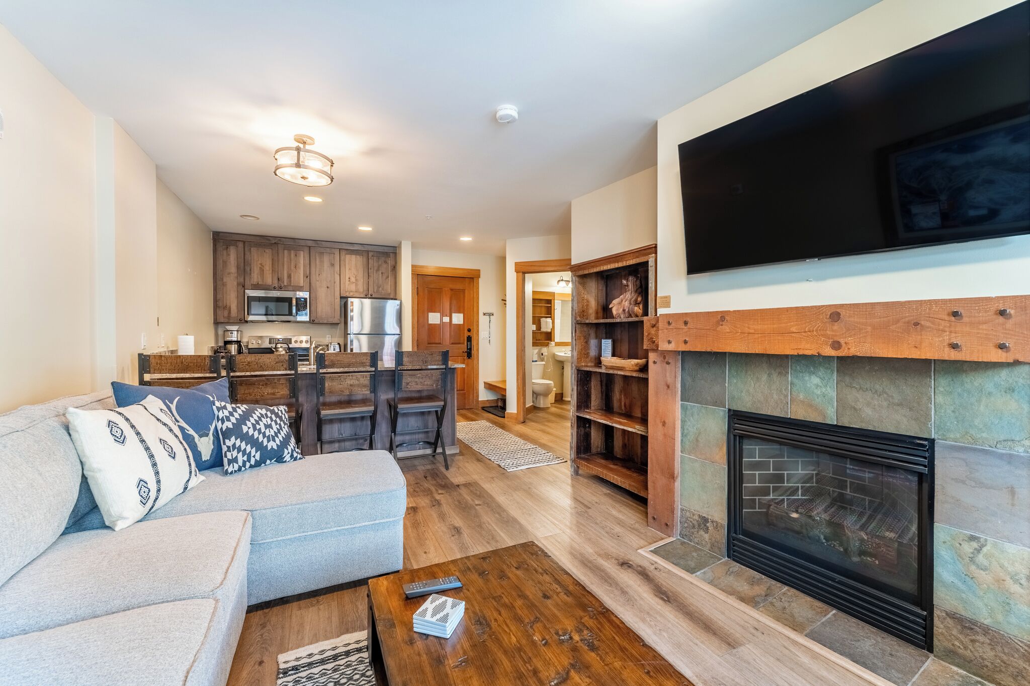 A modern living room with a fireplace, a dining area, and a kitchen.