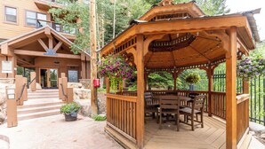 A wooden gazebo with a table and chairs, surrounded by a stone pathway and a wooden fence. - Springs #8875 By Summit County Mountain Retreats (Keystone)