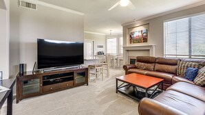 A living room with a television, leather sofa, coffee table, and a fireplace.