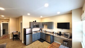 A modern kitchen with grey cabinets, a stainless steel refrigerator, a microwave, and a built-in oven. - Breckenridge Suites #6 - Cozy 1-Bedroom Suite with Fully Equipped Kitchen (Grove City)