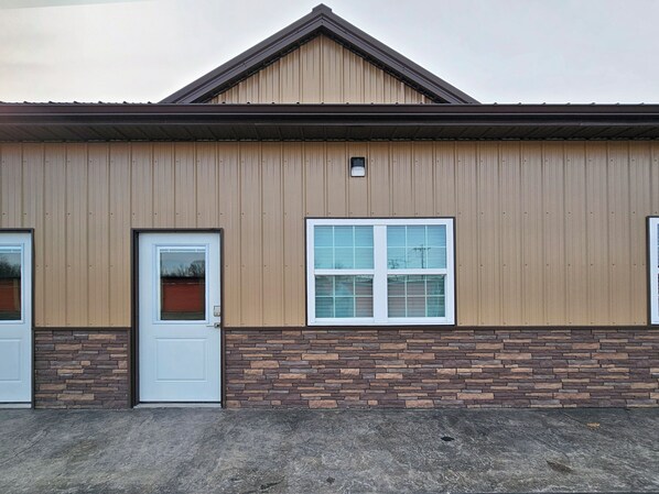 A building with a brown exterior, a stone base, a white door, and a window with a white frame.