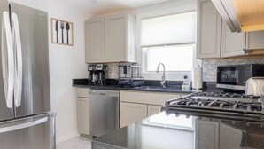 A modern kitchen with stainless steel appliances, a black countertop, and a window providing natural light. - Private Hudson Valley Escape (Kingston)