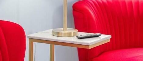 Une pièce moderne avec un lampadaire blanc sur une petite table, des chaises à revêtement rouge et une fenêtre laissant entrer la lumière naturelle.