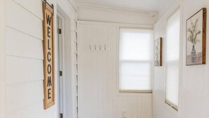 A hallway with a wooden welcome sign, a door, a window with blinds, and a door mat. - Private Hudson Valley Escape (Kingston)