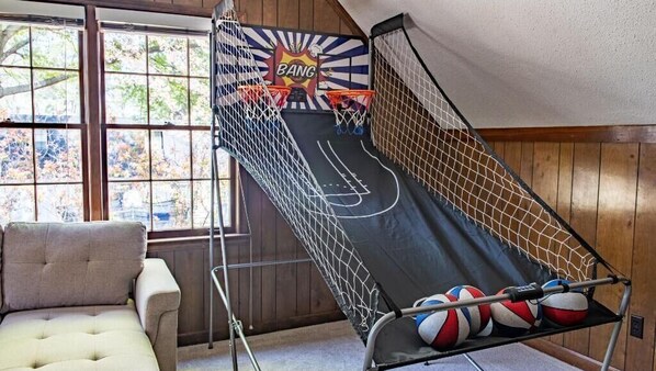 A basketball hoop with a net, a cushioned chair, and a basketball rack.