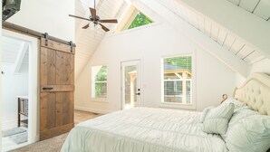 A bedroom with a large bed, a ceiling fan, and a skylight. - Smoky Mountains A-Frame (Sevierville)