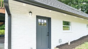 A white brick building with a dark gray door, a small window, and a light fixture above the door. - Smoky Mountains A-Frame (Sevierville)
