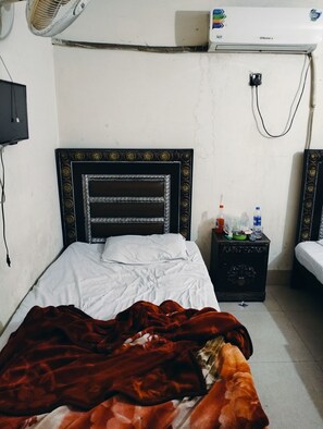 Cozy retreat with a single bed, nightstand, and air conditioning unit.