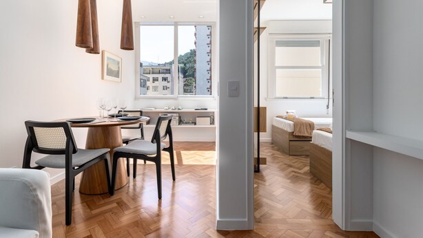 A modern interior with a dining area, wooden flooring, and a view of buildings outside.