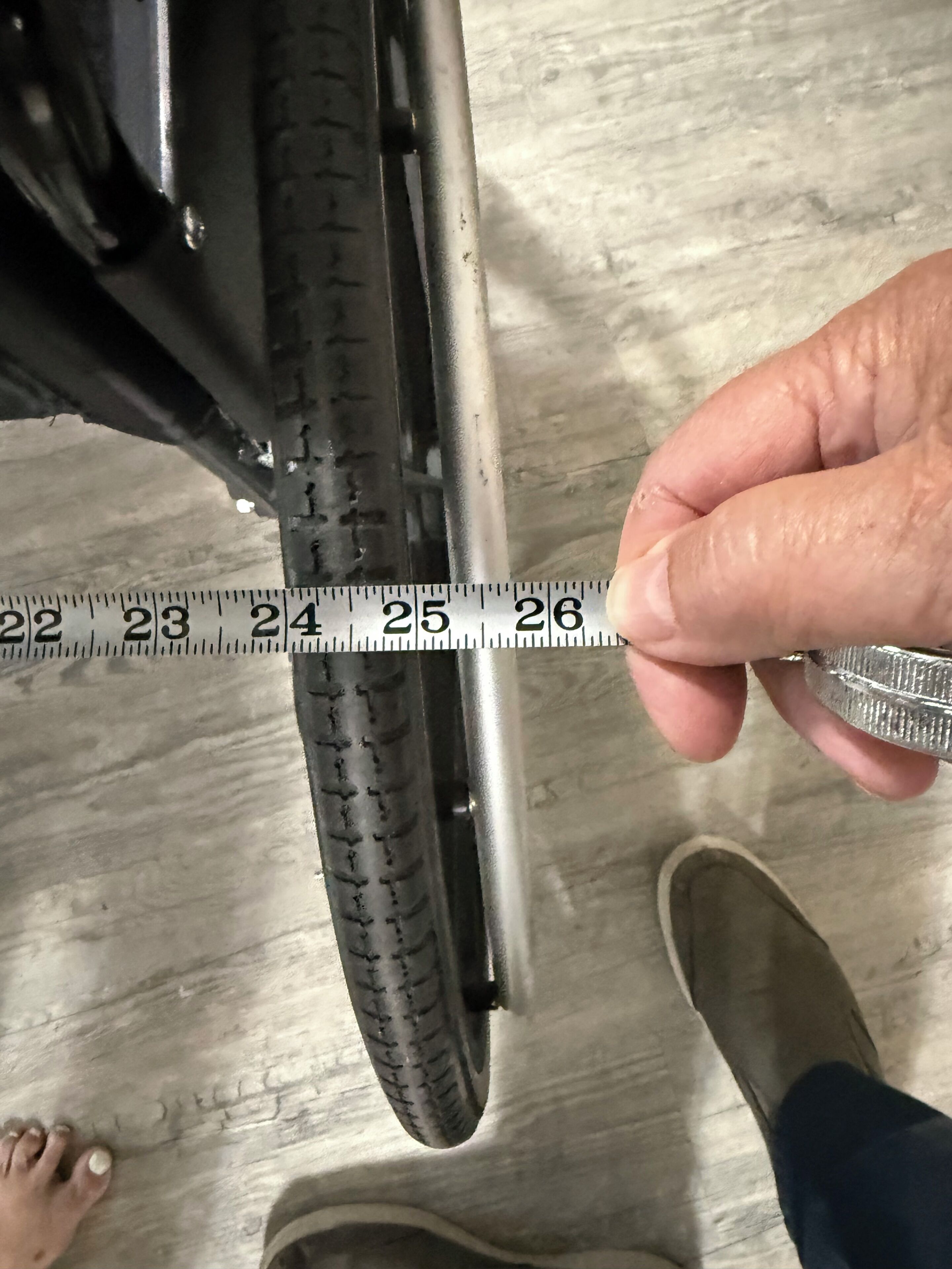 A person measuring the width of a tire with a ruler.