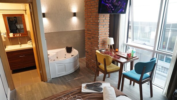 Une chambre d’hôtel avec une baignoire, un bureau avec une chaise, une télévision et une grande fenêtre.
