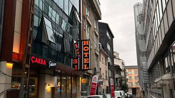 A hotel with a modern facade, a visible sign for 'CAKRA Palace', and a parked car on the street.