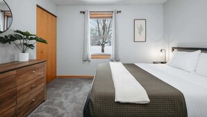 A bedroom with a bed, a dresser, a potted plant, a window with curtains, and a framed picture on the wall. - Green Lawn (Grawn)