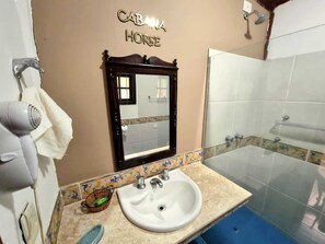 Uma casa de banho com lavatório, espelho e chuveiro.