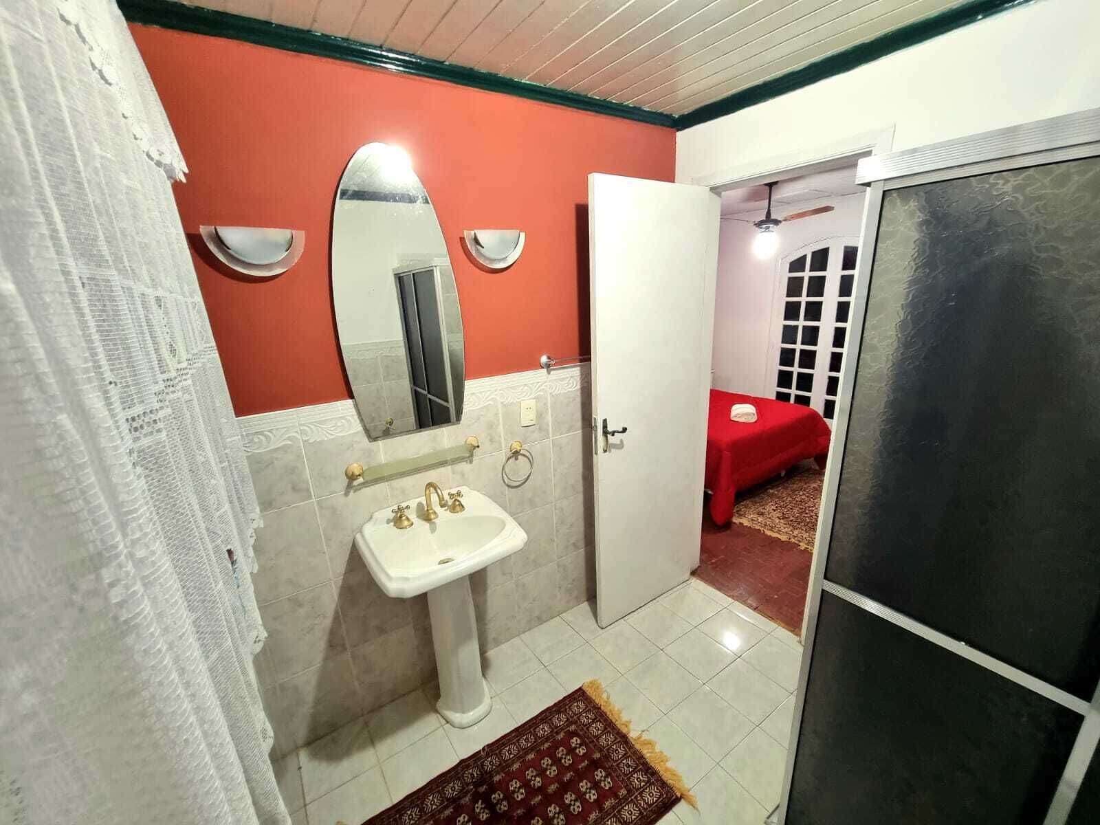 Un baño con un lavabo blanco, un espejo y una pared roja.