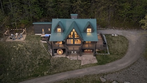 Une grande maison avec un toit végétalisé, de nombreuses fenêtres et une véranda.