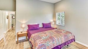 A bedroom with a large bed, two bedside tables with lamps, a wooden floor, and a window with blinds. - Peaceful Riverside Home w/ Patio, 7 Mi to Downtown (Riverside)