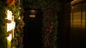 A spa area with a dark door, surrounded by lush greenery and red flowers. - Sivas Azze Palace Otel (Sivas)