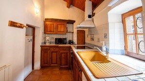 Cocina compacta con armarios de madera, microondas integrado y lavamanos con encimera de madera.