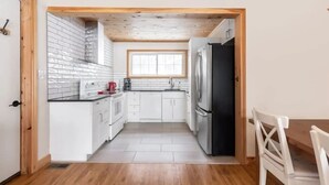 A compact kitchen with white cabinets, a black refrigerator, and a window above the sink. - Serene, breathtaking waterfront views in Muskoka, half an hour from Algonquin! (Huntsville)