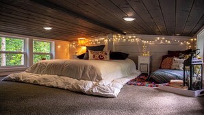 Un dormitorio acogedor con una cama grande, luces de adorno y una mesita de noche con un farol.