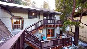 Ein zweistöckiges Haus mit einer Holzterrasse und einer Treppe, die zu der oberen Etage führt.