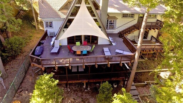 Ein Haus mit einer großen Terrasse, einem überdachten Sitzbereich und einem Schornstein.