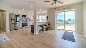 A spacious kitchen with modern appliances, a bar area, and a large sliding glass door leading to a balcony. - Intracoastal Retreat (Hubert)