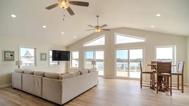 A spacious living room with a large sofa, a dining table with chairs, and a ceiling fan. - Intracoastal Retreat (Hubert)