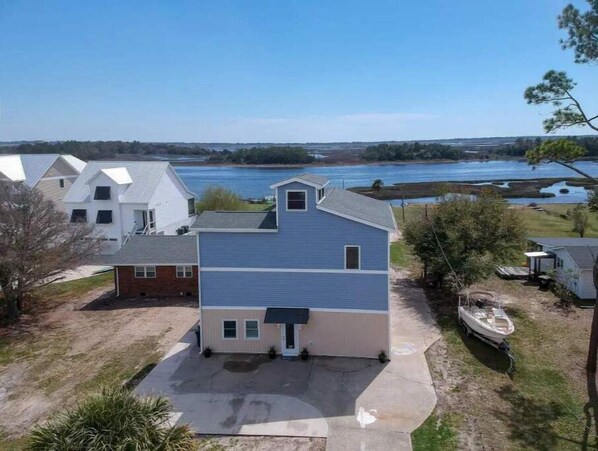 A two-story house with a large driveway and a boat docked outside.