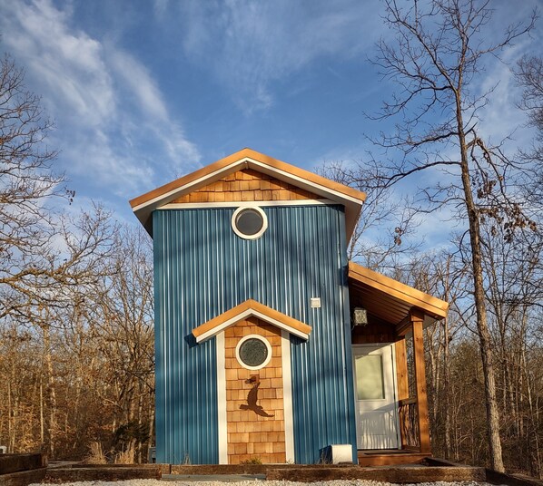 A two-story building with a wooden gable roof and a circular window on each floor. - The Nest, reconnect with that special someone in our charming birdhouse!  (Troy)